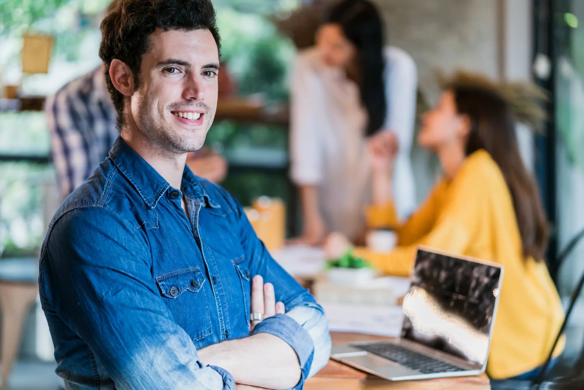Young business owner smiling with office in the background.